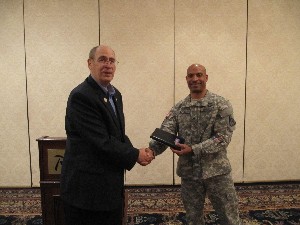Col. Fred Eisele, USA (Ret.), chapter vice president for programs, presents a TechNet Warfighter Pad to Col. Wayne Epps, USA, project manager for constructive simulation, Program Executive Office of Simulation, Training and Instrumentation, in recognition of his speech at the December meeting.